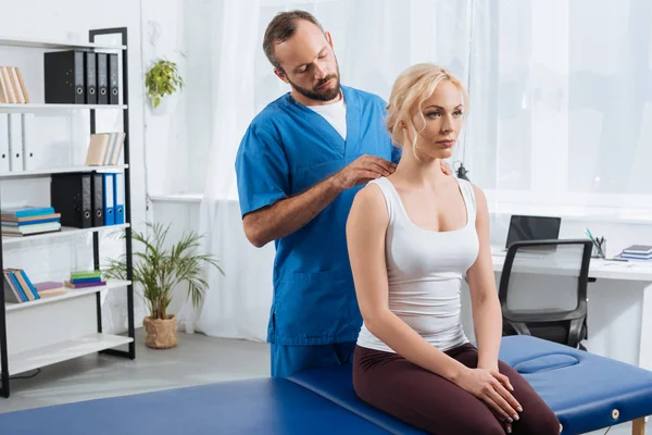 Physiotherapist massaging womans shoulders on massage table in hospital — Stock Photo