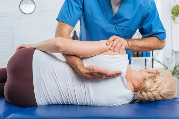 Colpo ritagliato di chiropratico che massaggia la schiena del paziente che giace sul lettino da massaggio in ospedale — Foto stock