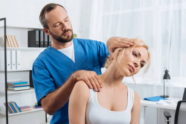 Portrait of chiropractor stretching neck of woman during appointment in hospital — Stock Photo