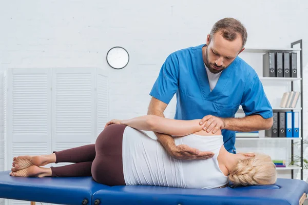 Quiropráctico masajeando la espalda del paciente que yace en la mesa de masaje en el hospital - foto de stock