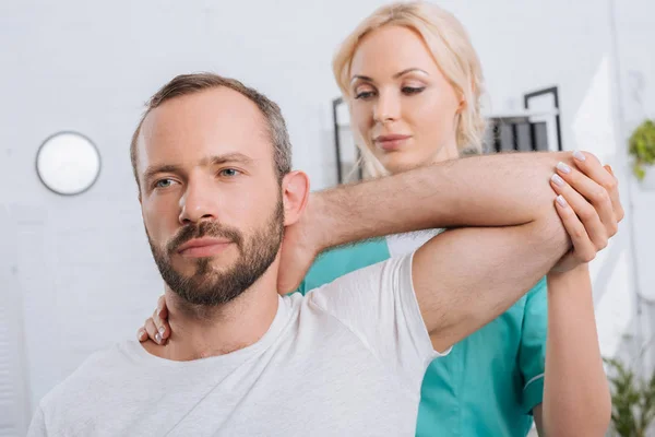 Портрет физиотерапевта растягивающего руки мужчин в больнице — стоковое фото