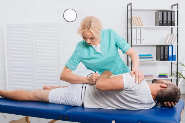 Female physiotherapist doing massage to patient on massage table in hospital — Stock Photo