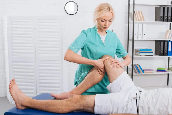 Partial view of chiropractor massaging patients leg during appointment in clinic — Stock Photo