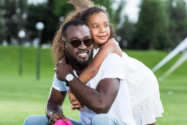 Entzückende afrikanisch-amerikanische Tochter umarmt Vater von hinten im Park — Stockfoto