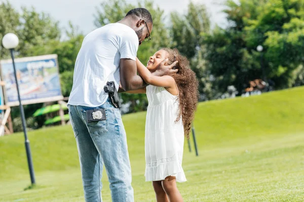 Afrikanischer amerikanischer Polizist umarmt entzückende Tochter im Freizeitpark — Stockfoto