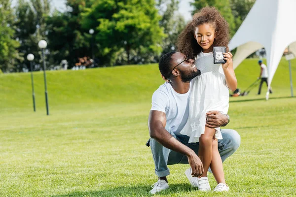 African american daughter standing with father police badge in park — Stock Photo