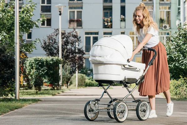Mãe andando e olhando para carrinho de bebê na rua — Fotografia de Stock