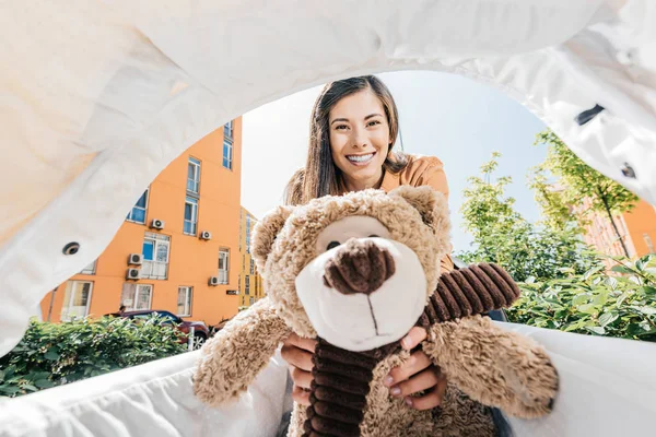Happy mother holding teddy bear in baby stroller — Stock Photo