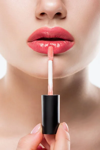 Обрізаний вид жінки, що наносить рожевий блиск для губ, ізольований на білому — стокове фото
