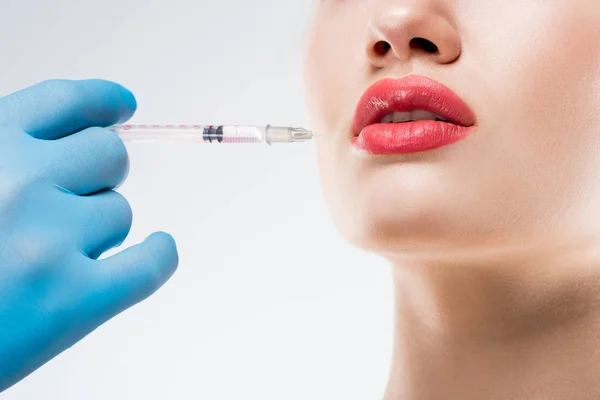 Cropped view of doctor making beauty injection in lips for woman, isolated on white — Stock Photo