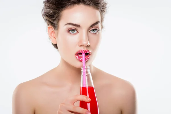 Atractiva chica desnuda con azúcar rosa espolvorea en los labios sosteniendo botella con bebida rosa y paja, aislado en blanco - foto de stock