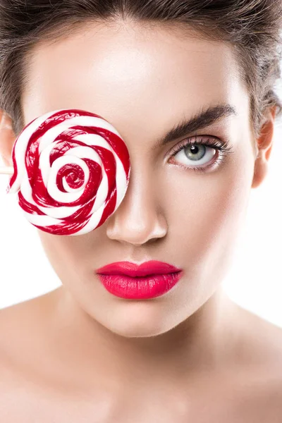 Beautiful fashionable girl holding red lollipop in front of eye, isolated on white — Stock Photo