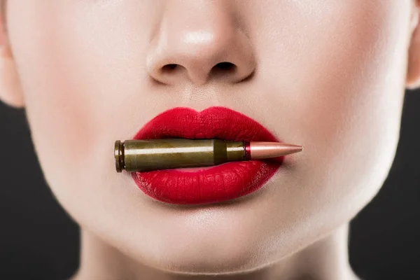 Vista recortada de la mujer sosteniendo bala en labios rojos, aislado en gris - foto de stock