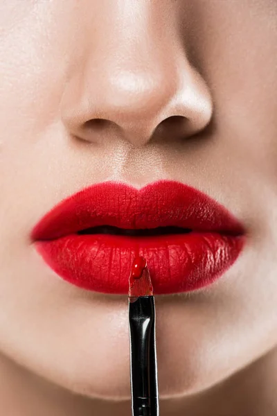 Vista ritagliata di ragazza che applica rossetto rosso con pennello cosmetico — Foto stock