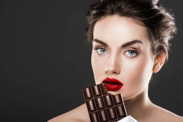 Attraente donna mangiare barretta di cioccolato, isolato su grigio — Foto stock