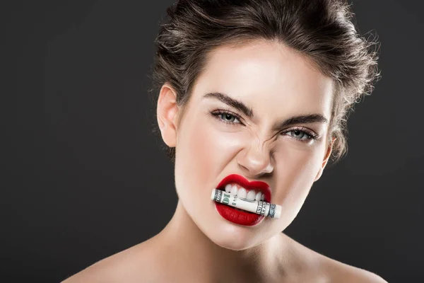 Mulher irritada atraente segurando dinheiro nos dentes, isolado em cinza — Fotografia de Stock