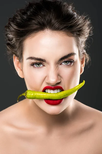 Portrait de femme tenant du piment vert dans les dents, isolé sur gris — Photo de stock