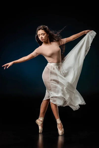 Елегантна танцівниця жіночого балету в білій спідниці танцює на темному фоні — стокове фото