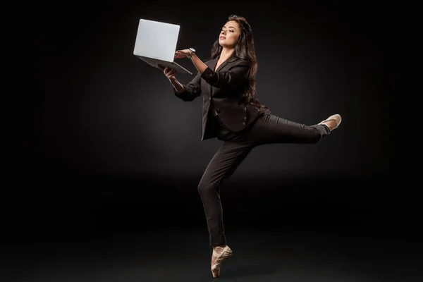 Femme d'affaires en costume et chaussures de ballet en utilisant un ordinateur portable sur fond noir — Photo de stock