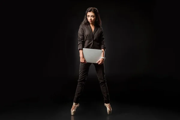 Beautiful businesswoman in suit and ballet shoes with laptop on black background — Stock Photo