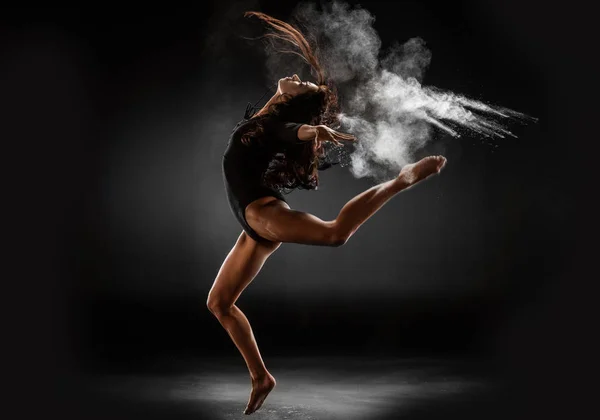 Young ballerina in black bodysuit with talc powder dancing on dark background — Stock Photo