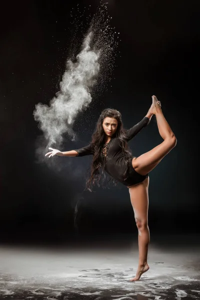 Young ballerina in black bodysuit with talc powder dancing on dark background — Stock Photo