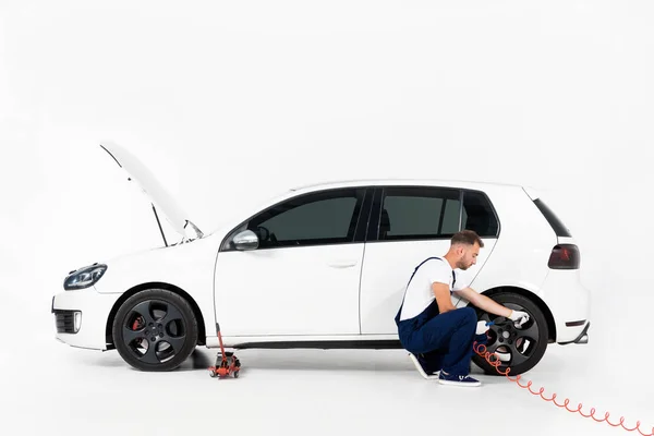 Automechaniker in blauer Uniform beim Reifenaufpumpen und Luftkontrolle mit Manometerdruck auf weiß — Stockfoto