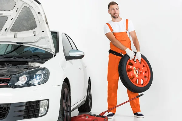 Automechaniker trägt Autoreifen auf weißem Grund — Stockfoto