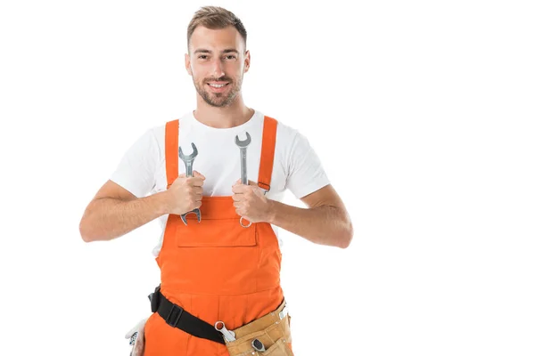 Lächelnder gutaussehender Automechaniker in orangefarbener Uniform, der Schraubenschlüssel isoliert auf weiß zeigt — Stockfoto