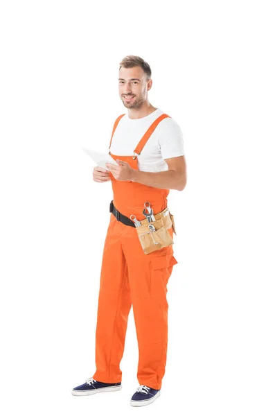 Lächelnd schöner Automechaniker in orangefarbener Uniform, Tablette isoliert auf weißem Grund haltend — Stockfoto