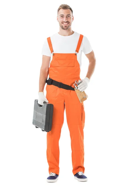 Smiling handsome auto mechanic in orange uniform holding toolbox isolated on white — Stock Photo