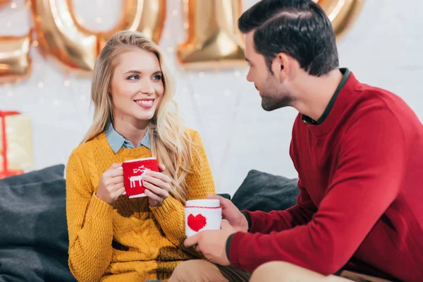 Casal feliz segurando copos de café de Natal e olhando um para o outro — Fotografia de Stock