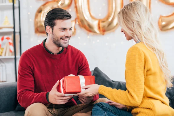 Happy beautiful couple gifting present at home with 2019 golden balloons — Stock Photo