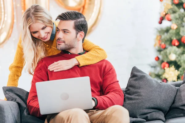 Young happy couple using laptop at home on new year — Stock Photo