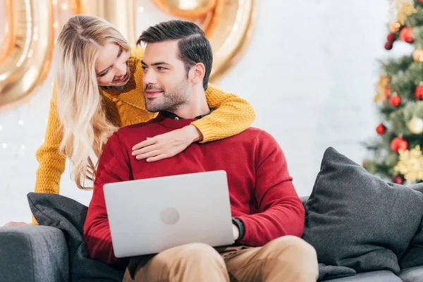 Couple heureux en utilisant un ordinateur portable à la maison la veille de Noël — Photo de stock