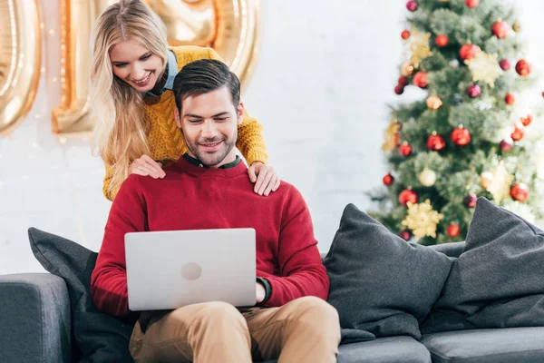 Casal feliz usando laptop juntos em casa no Natal — Fotografia de Stock