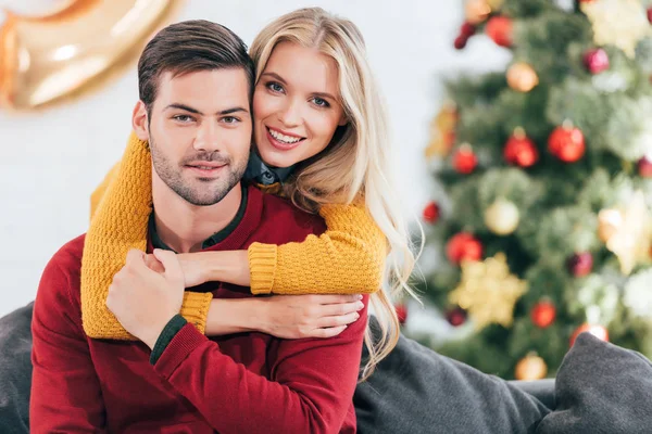 Glückliche Frau umarmt ihren Freund zu Hause mit Weihnachtsbaum — Stockfoto