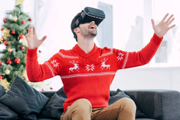 Excité homme gestuelle et en utilisant casque de réalité virtuelle pendant la veille de Noël — Photo de stock