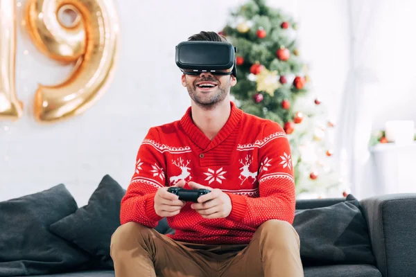 Happy man with virtual reality headset and joy pad playing video game during 2019 new year — Stock Photo