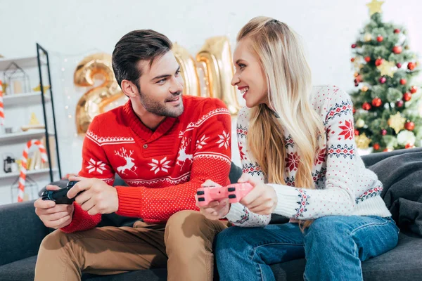 Young couple playing video game with joysticks on christmas eve — Stock Photo