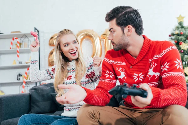 Joven pareja jugando video juego con joysticks en la víspera de Navidad - foto de stock