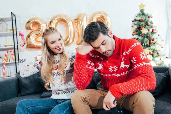 Пара грає у відеоігри з джойстиками вдома з новорічними кульками 2019 року — стокове фото