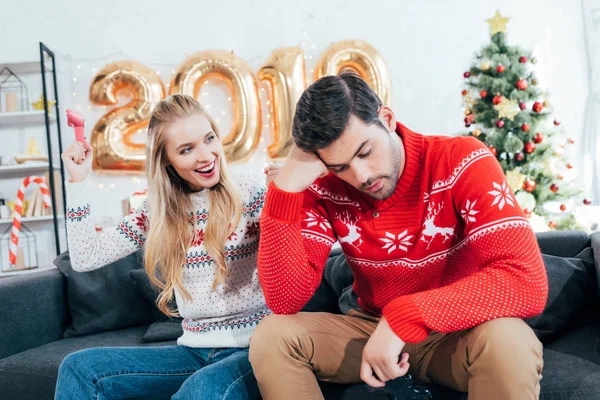 Pareja jugando videojuego con joysticks en casa con 2019 globos de año nuevo - foto de stock