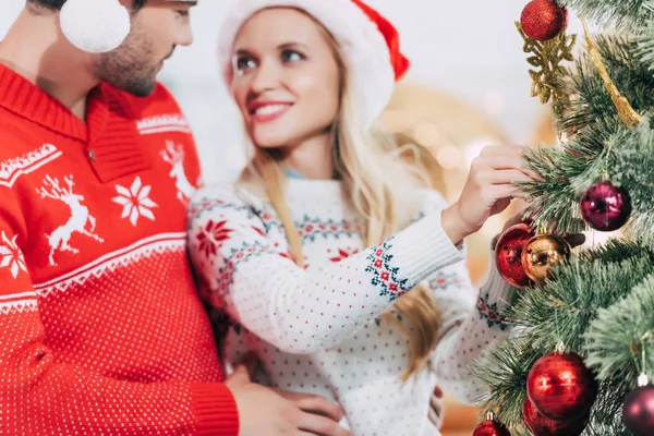 Enfoque selectivo de pareja joven decorando árbol de Navidad juntos - foto de stock