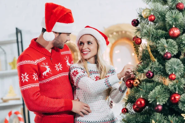 Joven pareja feliz decorando árbol de Navidad juntos - foto de stock