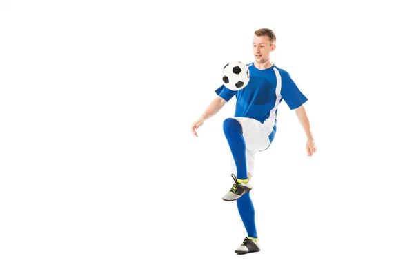 Full length view of athletic young sportsman in soccer uniform training with ball isolated on white — Stock Photo