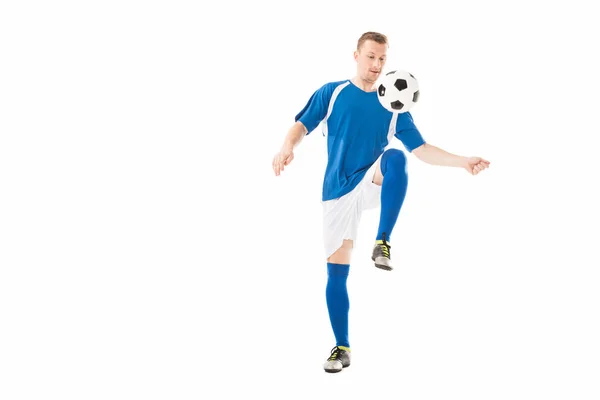 Athletischer junger Sportler in Fußball-Uniform beim Training mit Ball auf weißem Untergrund — Stockfoto