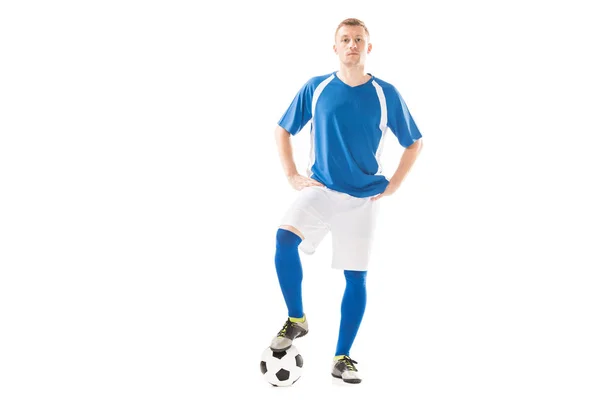 Confiado joven jugador de fútbol de pie con las manos en las caderas y mirando a la cámara aislada en blanco - foto de stock