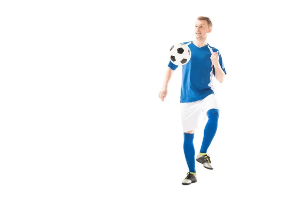 Full length view of smiling young sportsman playing with soccer ball and looking away isolated on white — Stock Photo