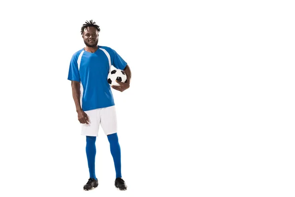 Vista completa del atlético afroamericano deportista sosteniendo pelota de fútbol y sonriendo a la cámara aislada en blanco - foto de stock